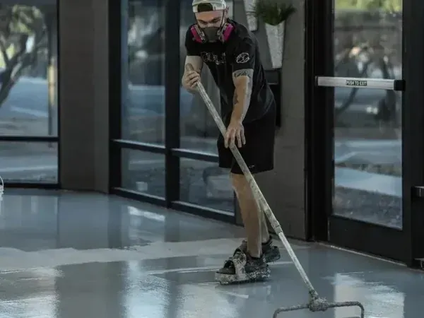 Contractor applying epoxy floor coating with a squeegee during installation