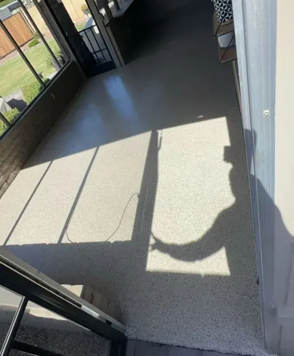 Epoxy floor coating installed in screened porch area with smooth finish and natural light shadows.